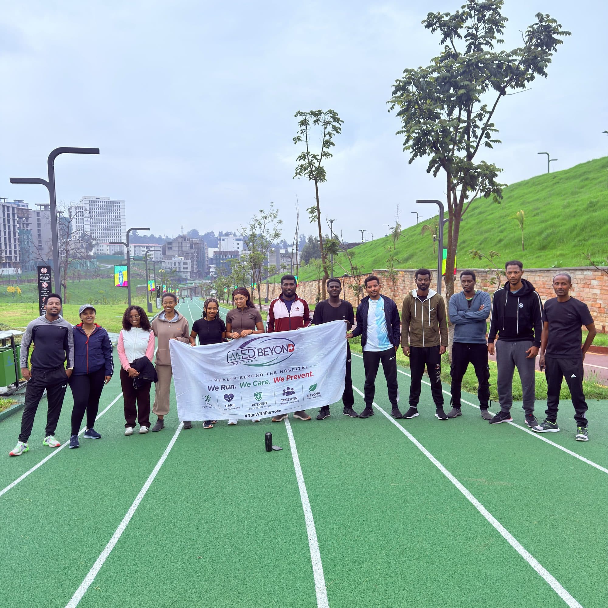 MedBeyond Run Club members gathered on a running track in Addis Ababa, holding the club banner